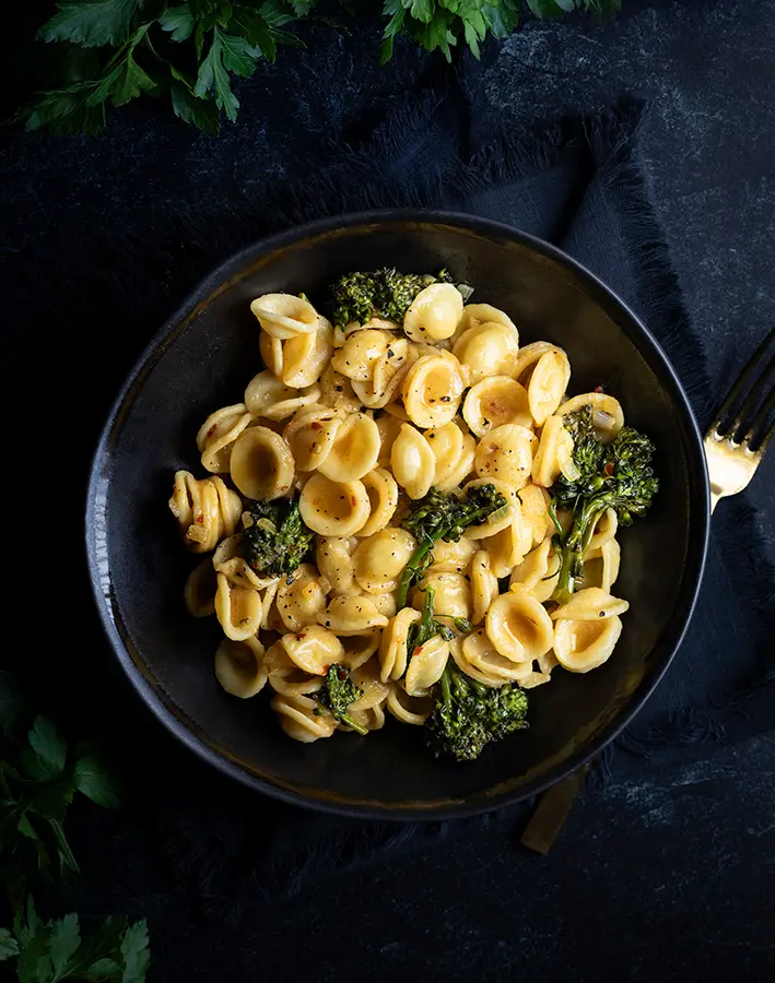 Pasta with broccoli in a black bowl.